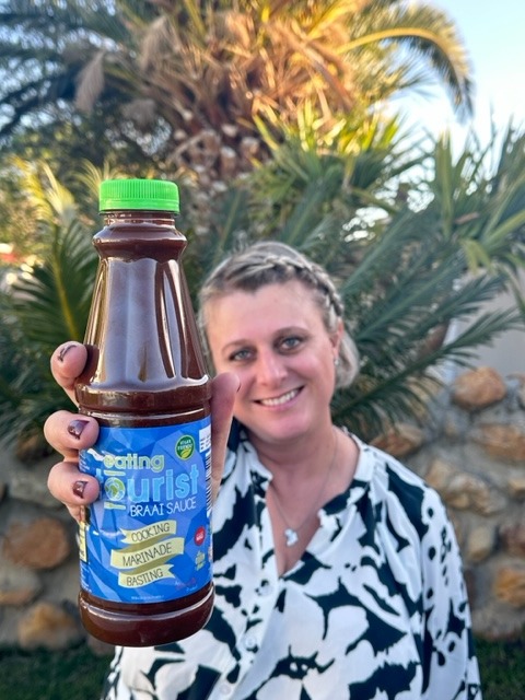 A photo of me holding my signature product the Eating Tourist Braai Sauce in my hand.