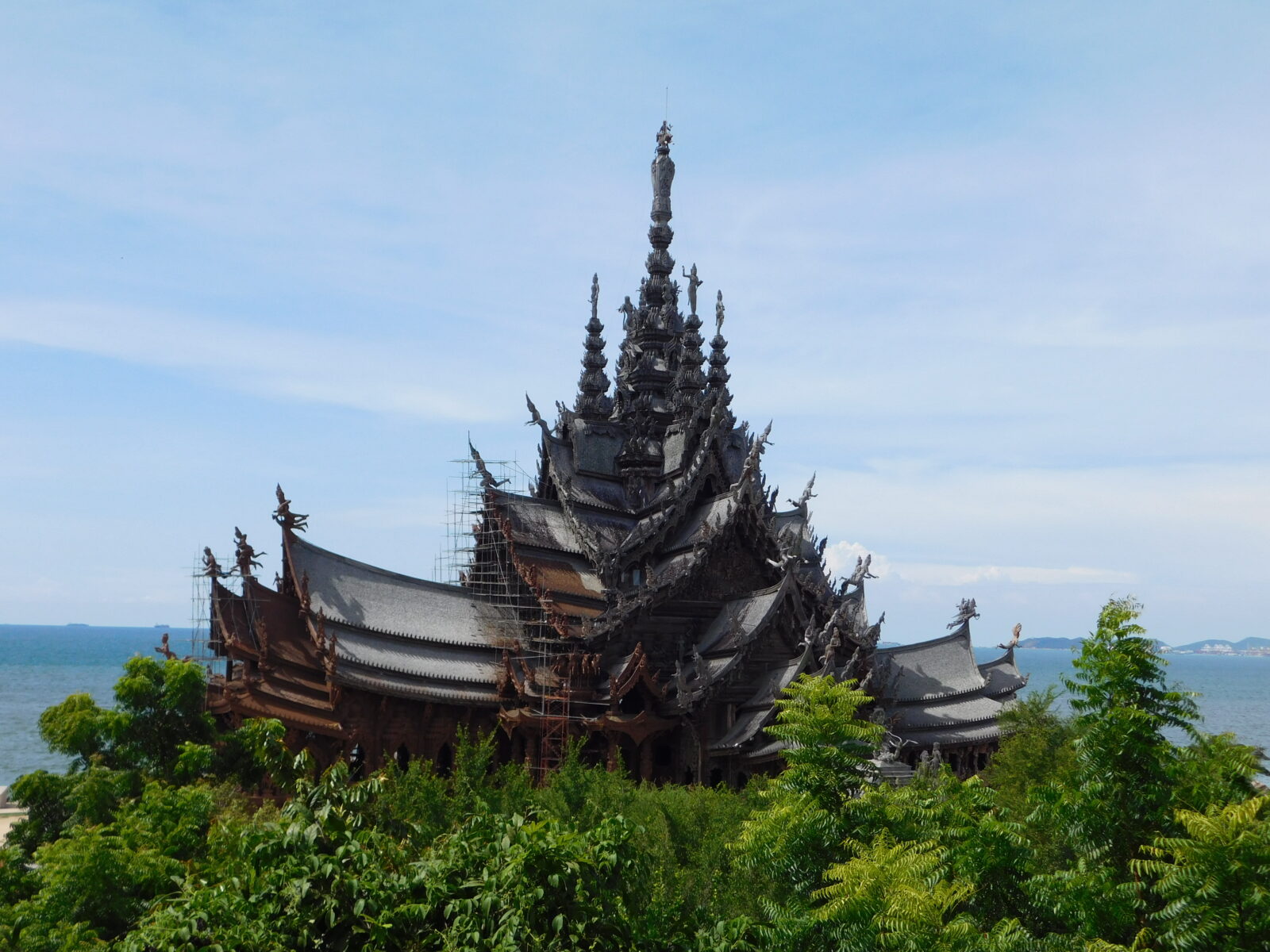 A photo of The Sanctuary of Truth in Pattaya in Thailand. The whole temple is made out of wood in a beautiful setting of beach and trees.